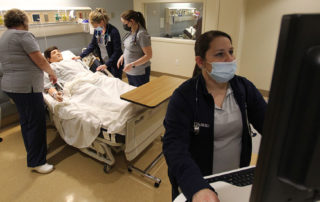 Nursing students work on a simulation patient.