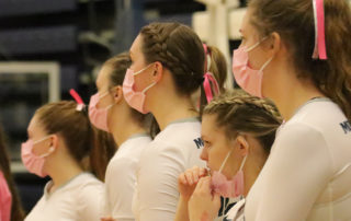 Volleyball players stand on the sidelines during the Pink Out Game 2020