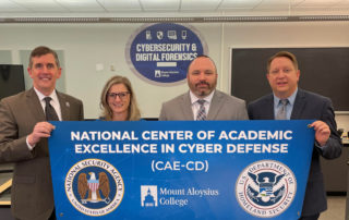 John McKeegan, President of Mount Aloysius College; Kristi Smith, Information Technology Department Chair; Dr. Christopher Lovett, Academic Dean; and Dr. David Haschak, Vice President for Academic Affairs stand with a “Center of Academic Excellence for Cyber Defense” banner in the Cybersecurity & Digital Forensics Research Center on the campus of Mount Aloysius College.