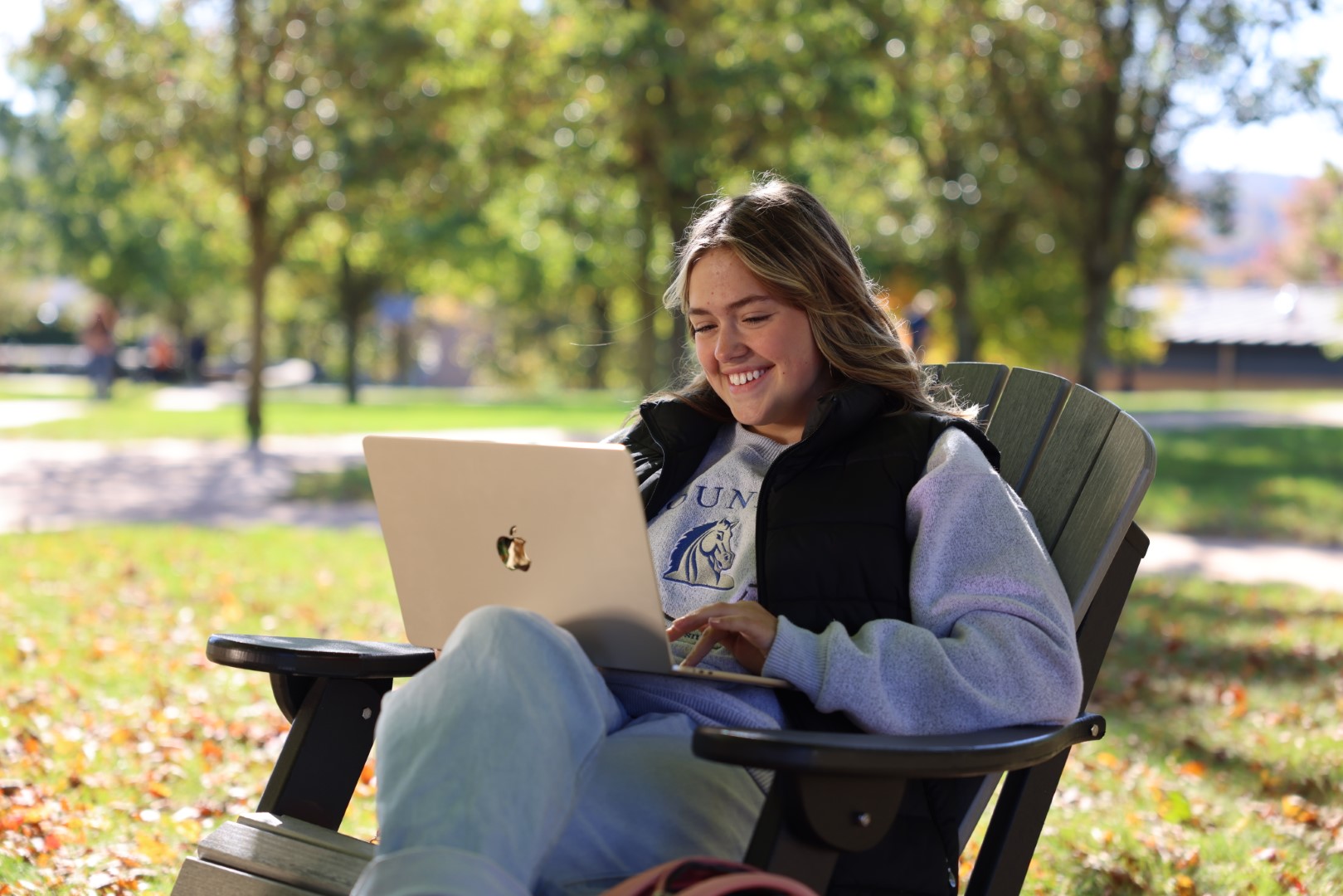A student sits outside with her laptop