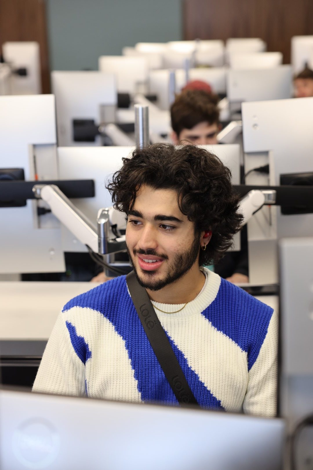 A male IT student sits at a computer in the cybersecurity lab.