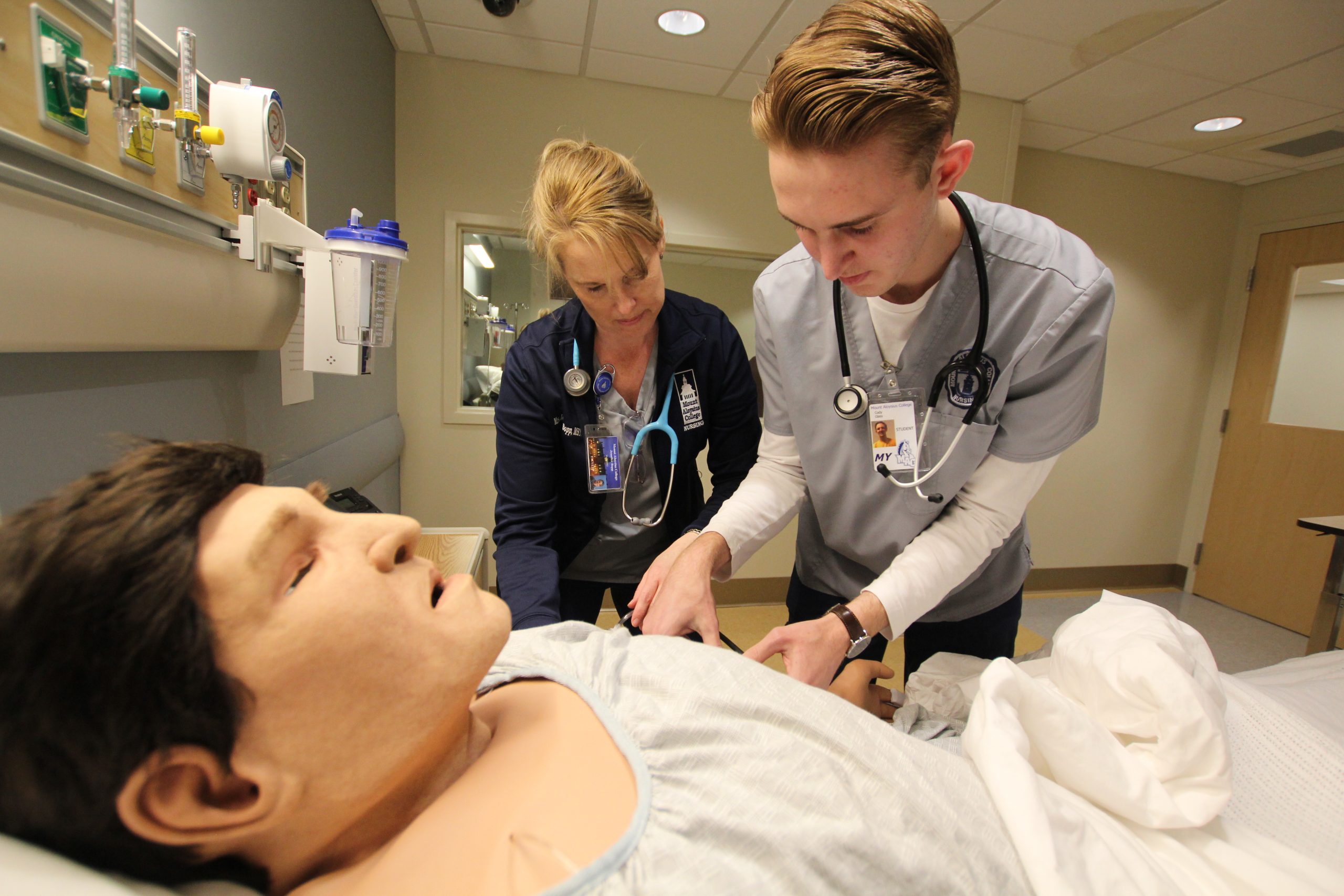 A nursing professor and a nursing student work on one of the mannikins in the nursing simulation lab.
